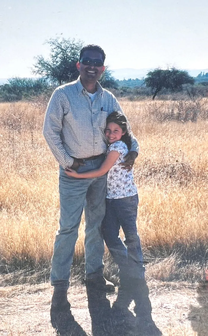 Mario Ortiz with his young daughter Olivia in a dry pasture.